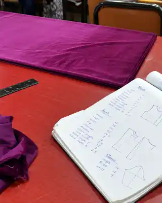 Purple fabric and tailoring pattern notebook on a worktable